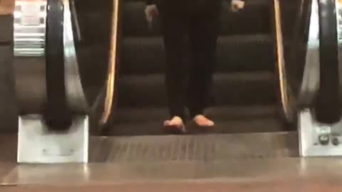 Lady black jacket with hammer and sandals walking backwards escalator