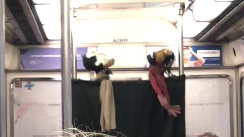 Puppet show on subway ride, two puppets in red and white shirt sing together