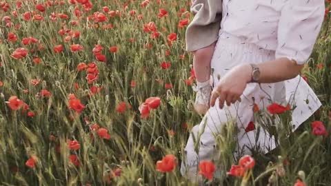 Woman Walking on Red Poppy Flower Field While Carrying Her Baby