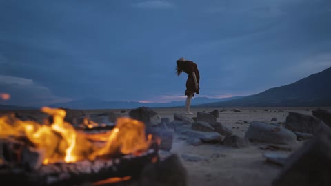 Deserted plain with a campfire and a woman practicing yoga