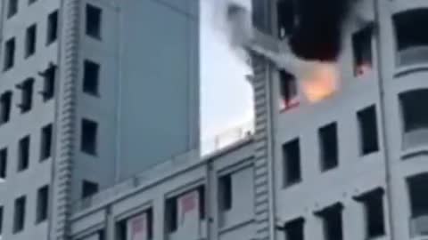 A drone extinguishes a fire in a burning high-rise building.