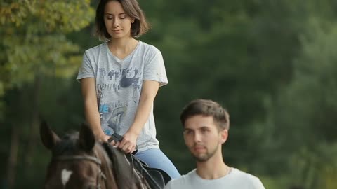 Young couple having fun on weekends. A girl riding a horse with her boyfriend