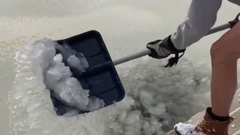 2 crazy men break ice in a frozen pond and take an ice bath in it