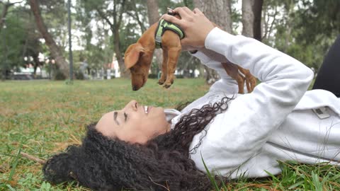 Girl lying on the grass holding her little dog on top