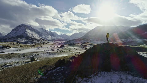 Silhouette of backpacker walking towards the edge of a rocky peak to contemplate the beautiful panor