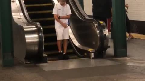 A little boy in white bottom of opposite escalator