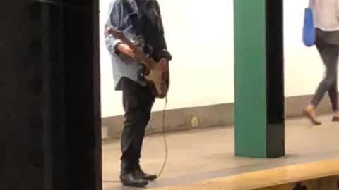 Guy denim jacket playing electric guitar subway