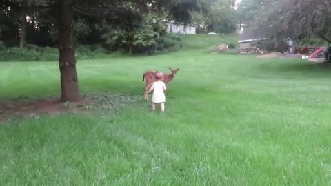 A little girl is playing with a roe deer