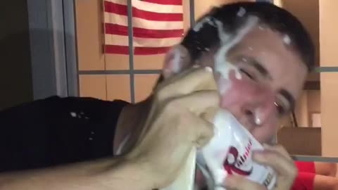 Guy in black shirt cracks beer open on his head its spills everywhere