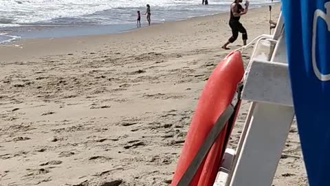 Guy in black punching air at beach