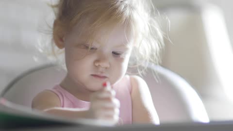 A Cute Baby Girl Coloring with Crayons