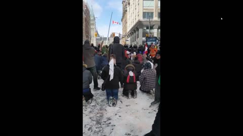 Protestors in Ottawa Kneel in Prayer to God as jackboots surround them.