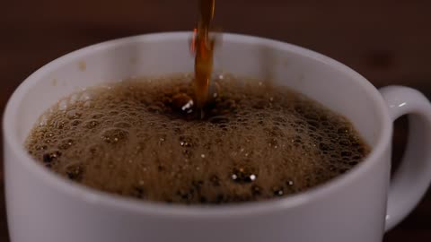 Filling a white cup of coffee