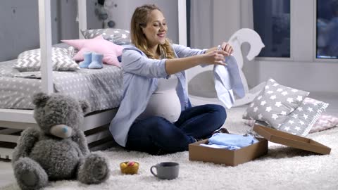 Pregnant woman looking at baby clothes