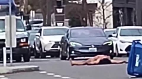 naked Trans activist covered in an LGBTQI+ flag blocks traffic in Seattle