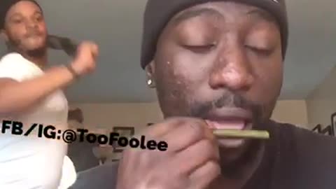 Man rolling a blunt gets whipped in the head by friend