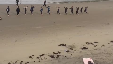 Surfboards laid out on beach surfers doing yoga on sand