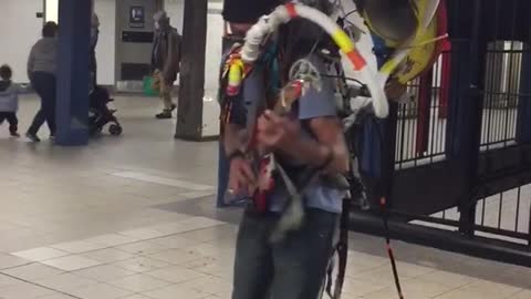 Old man blue shirt drums on back playing guitar