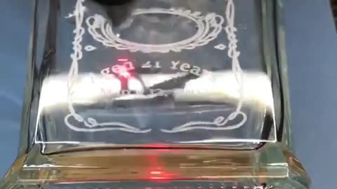 CO2 laser engraving a glass whiskey bottle with a wedding / best man themed design