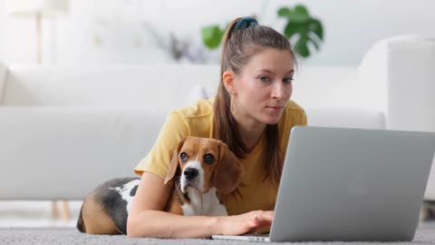 Woman with dog on floor browse internet, relax with gadget and cute pet beagle