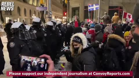 CANADIAN PROTESTORS PUT FLOWERS ON THE GROUND IN FRONT OF RIOT POLICE