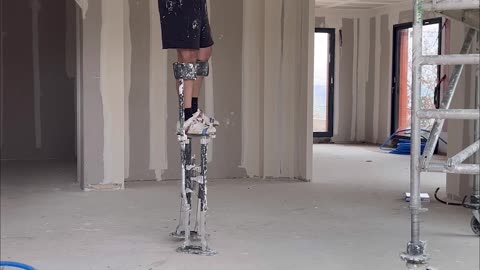 Worker on Stilts Shows How to Pick up Dropped Tool