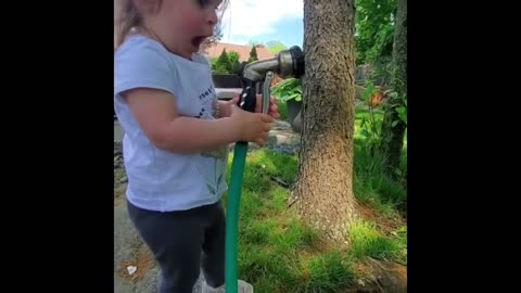 Toddler hilariously tries to catch water from garden hosee