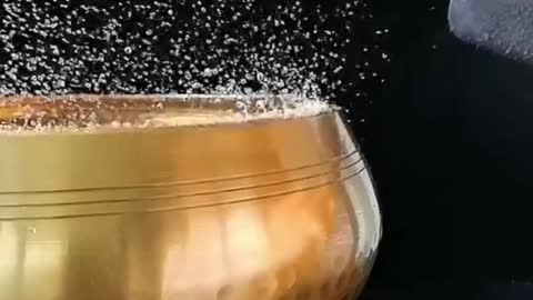 A glass full of water drops like pearls as gravity strikes