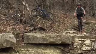 Man in grey rides dirt bike falls onto rocks