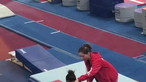 Girl at gymnastics lesson falls down on blue mat