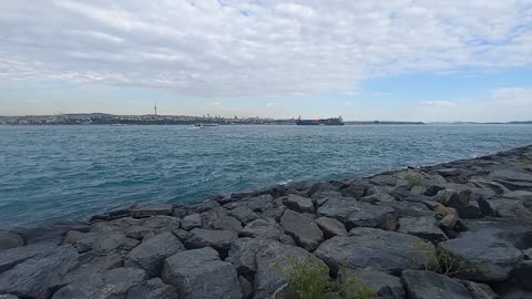 A beautiful natural view of sea waves with rocks and a ship