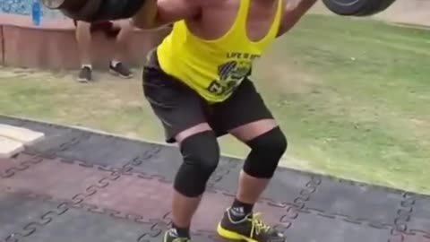 Elderly Fitness Coach Does Squats While Lifting Heavy Barbell