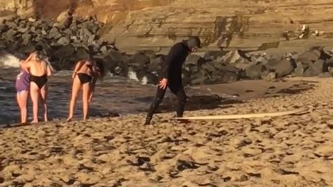 Guy in black wet suit laying on yellow surf board