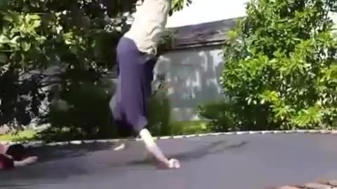 Boy in blue shirt does flip on trampoline lands on shoulder