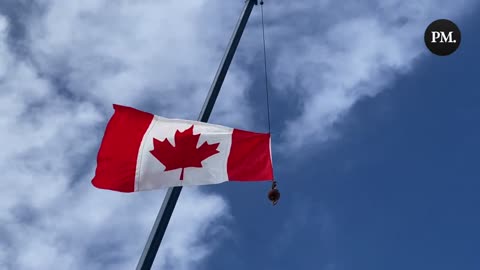 Supporters of the Freedom Convoy sing O Canada as they raise a Canada flag.