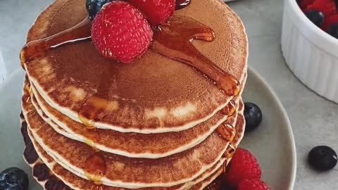 Person Pouring Honey on Pancakes