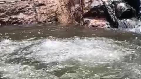 Slo-mo video guy slides down small waterfall