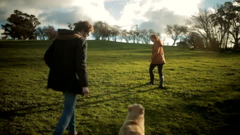 Yong couple walking dog at sunset.