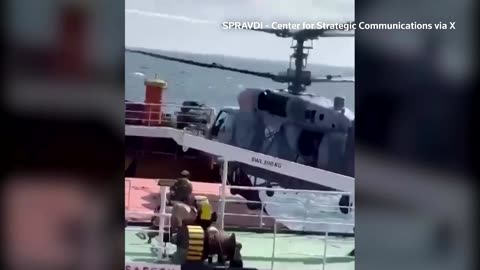 Russian soldiers board helicopter from stopped ship