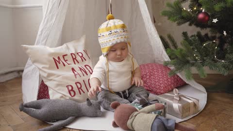 A Baby Playing on the Floor beside a Christmas Tree