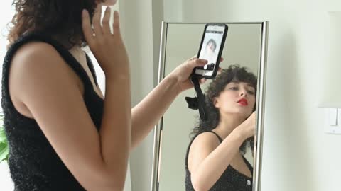 Woman in Black Dress Taking Selfie by the Mirror