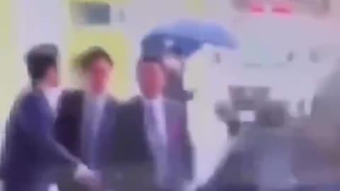 A bodyguard blocks an explosive, kicks it away, and quickly unfolds a shield while evacuating the Japanese Prime Minister