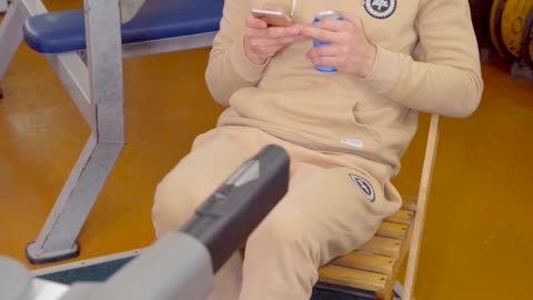 Man doing exercises on the treadmill while sitting on a chair, drinking a soda.