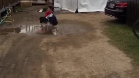 Guy in black clothes and red shoes cannonballs into puddle