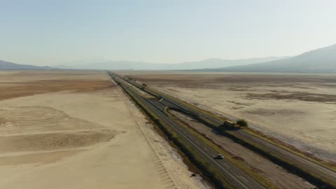 Dare to watch :An asphalt road with vehicle traffic traverses,desert terrain under the scorching sun