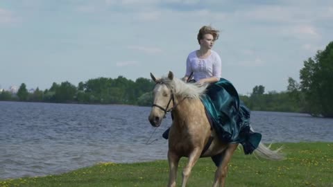 Young beautiful woman rider riding a white horse on the field