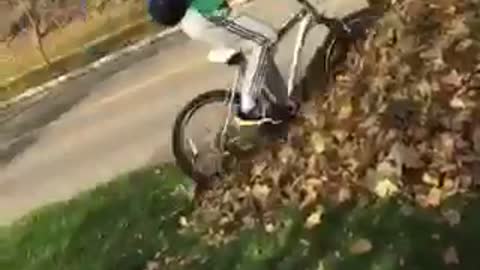 Guy in green shirt riding bike falls down