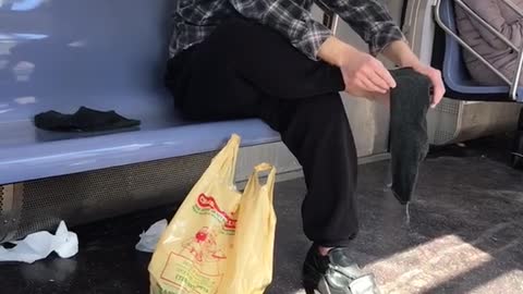 Man rubs bare foot on subway train