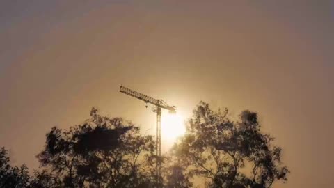 Tower crane during sunset seen in the distance