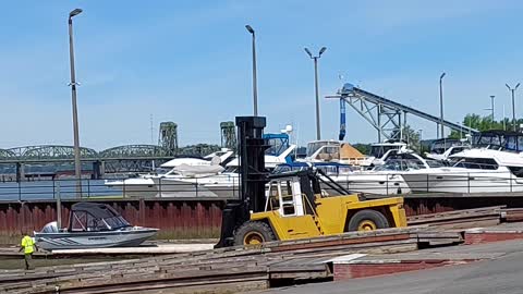 Large Forklift Lowering a Boat Into the Water at a Dry Dock Marina